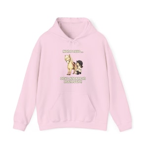 Può includere: Una felpa con cappuccio rosa chiaro con tasca frontale e cappuccio con coulisse. Il davanti presenta un'illustrazione di un pony e una persona con la scritta "Non posso... Devo andare in maneggio!"