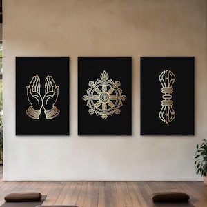 Peut inclure: Un ensemble de trois impressions murales rectangulaires sur fond noir avec des illustrations en lignes dorées. L'impression de gauche montre des mains en prière, celle du centre une roue du dharma et celle de droite un symbole vajra.