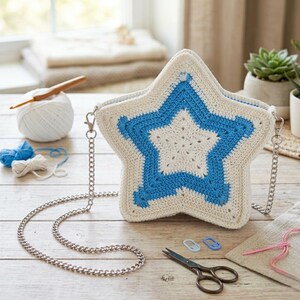 May include: A star-shaped crochet bag in cream and blue with a silver chain strap. The bag features a large blue star design on a cream background. Crochet supplies, including yarn and scissors, are visible.