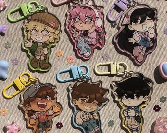 Op de afbeelding: Zes acryl sleutelhangers met gestileerde anime-geïnspireerde personages en kleurrijke plastic karabijnsluitingen. Elke bedel toont een uniek personage in vrijetijdskleding, met levendige omlijningen en een basis van transparant acryl.
