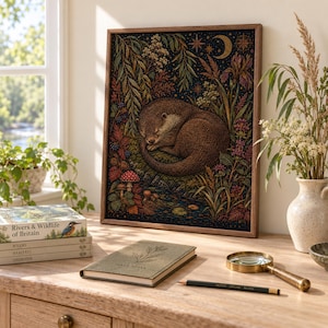Könnte beinhalten: Ein gerahmter rechteckiger Kunstdruck mit einer detaillierten Illustration eines braunen Otters, der zusammengerollt inmitten von dunklem Laub, bunten Wildblumen, Pilzen und einer Mondsichel am Nachthimmel schläft, in einem Holzrahmen.