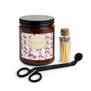 May include: A brown candle jar with a black lid, a small glass jar of matches, and a black candle wick trimmer. The candle jar has a floral design and the text "Collect moments not things."