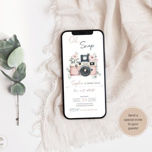 Może przedstawiać: Różowy i biały cyfrowy ekran telefonu z zaproszeniem na urodziny z okazji dwunastych urodzin Sophii. Zaproszenie przedstawia zabytkowy aparat fotograficzny z różowymi i białymi kwiatami. Tekst brzmi: "Oh Snap! Sophia kończy dwanaście lat! Dołącz do nas, aby świętować! 25 września o 12:30 1234 Floral Camera Drive, Woodland Hills, CA 91367 RSVP: [numer telefonu]"