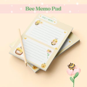 May include: A stack of bee-themed memo pads with lined pages, featuring illustrations of bees, honey pots, and flowers. A wooden pencil rests on the pads. The pads have a light yellow background with the text "Bee Memo Pad" at the top.