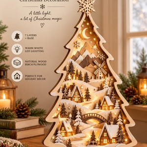 May include: A 3D layered laser-cut birch plywood Christmas tree decoration featuring a winter village scene with houses, a bridge, a windmill, and mountains. The tree is illuminated with warm white LED lighting and topped with a snowflake.