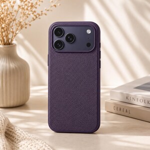 May include: A dark purple smartphone case with a textured, cross-hatched surface finish. The case features a raised, rectangular camera module cutout in a matching dark purple tone, designed to accommodate three circular lenses and a flash.