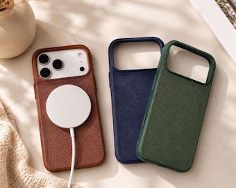 May include: Three rectangular smartphone cases with textured surfaces in brown, navy blue, and dark green. The brown case is attached to a white circular magnetic wireless charger with a cord. Each case features a large cutout for the camera lens.