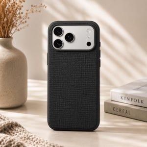 May include: A black smartphone case with a textured fabric-like finish on the back. The camera module area is rectangular with a silver-toned plate, featuring three circular camera lenses and a small circular flash component arranged vertically.