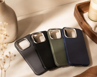 May include: Four rectangular smartphone cases arranged in a row, featuring a smooth matte finish in shades of dark gray, black, olive green, and navy blue. Each case includes a metallic silver-toned square camera cutout frame at the top corner.