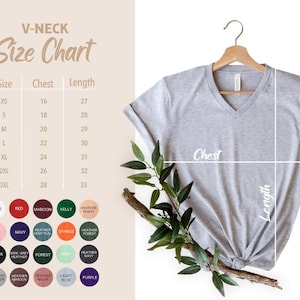 May include: A heather gray V-neck t-shirt on a wooden hanger with a size chart showing chest and length measurements in inches. The chart lists sizes from XS to 3XL. Below the chart are twenty circular color swatches for available shirt options.