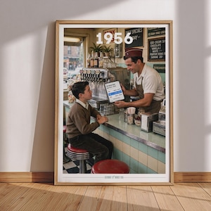 May include: A framed wall art print titled 1956 featuring a vintage diner scene. A person in a brown sweater sits at a counter while a server in a white shirt and apron holds a tablet. The background shows a soda fountain, menu boards, and stools.