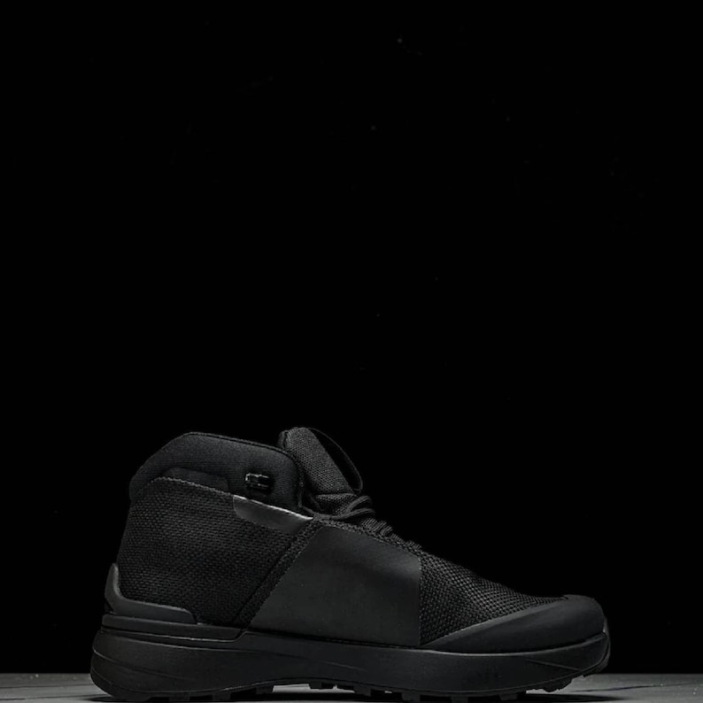 May include: Black hiking boot with a high-top design. The boot features a mesh and leather upper, a padded collar, and a thick, textured sole. The boot is designed for outdoor activities and provides ankle support.