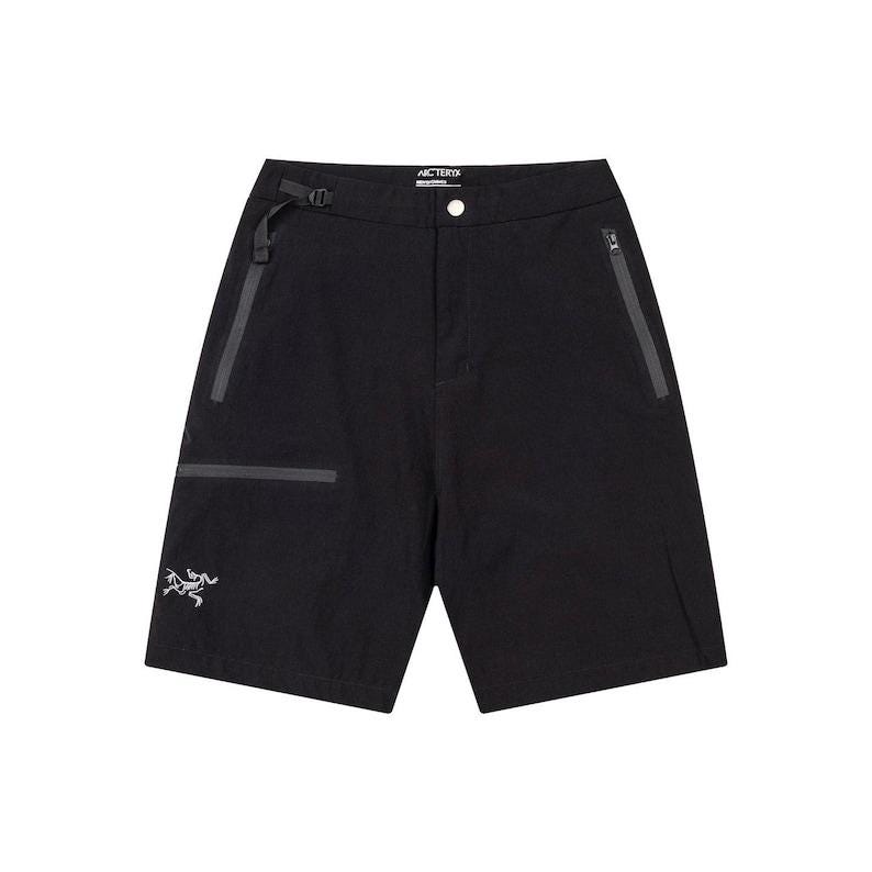 May include: Black shorts with a button closure and a buckle belt. The shorts have two zippered pockets and a small logo on the left leg. The brand name is visible on the waistband. These shorts are suitable for outdoor activities.
