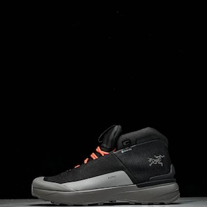 May include: Black and grey hiking boot with orange laces. The boot has a mesh upper, a grey sole, and the word "KOPEC" printed on the side. The Arc'teryx logo is visible on the side of the boot.