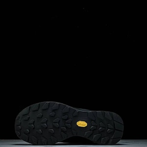 May include: Black hiking boot sole with a textured pattern and a yellow Vibram logo. The sole is designed for grip and durability, suitable for outdoor activities. The boot is likely for hiking or trail running.