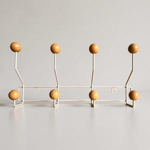Puede incluir: Un perchero de pared con estructura de metal blanco y ocho ganchos con extremos de madera de color marrón claro. El perchero cuenta con cuatro ganchos superiores y cuatro inferiores dispuestos simétricamente, con dos orificios de montaje.