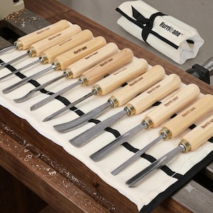 May include: A set of ten woodturning chisels with light-colored wooden handles and metal blades, arranged in a white canvas tool roll with black ties. The brand name Hurricane is printed on the handles and the tool roll in black lettering.