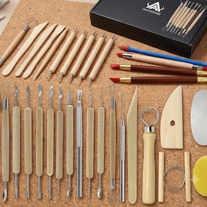 May include: A comprehensive set of pottery and clay sculpting tools including wooden-handled wire loops, metal scrapers, modeling sticks, and silicone-tipped brushes. The collection features a black box labeled AUGERNIS and various metal and wood implements.