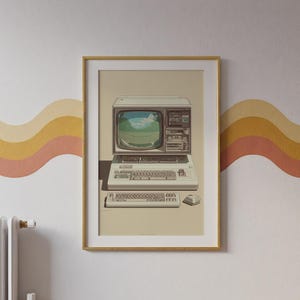 May include: A framed art print featuring a vintage beige computer with a bulky monitor displaying a green landscape, a built-in disk drive, a mechanical keyboard, and a separate matching keyboard and mouse, all set against a solid beige background.