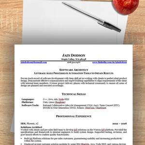 May include: A printed resume for Jain Dodson, Software Architect, featuring contact details, technical skills in C++, Java, and Ada, and professional experience at IBM. A black ballpoint pen rests on the paper, accompanied by two green apples and one red apple.