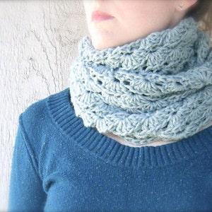 Może przedstawiać: Jasno błękitny, szydełkowy komin. Komin wykonany jest delikatnym wzorem i idealnie nadaje się do utrzymania ciepła w zimie.