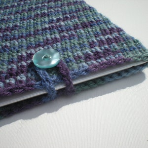 May include: A blue, green, and purple knitted laptop sleeve with a light blue button closure.