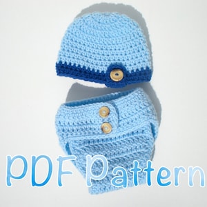 May include: A light blue crochet baby hat and diaper cover set. The hat has a dark blue brim and a wooden button detail. The diaper cover has two wooden buttons. The text "PDF Pattern" is in the image.