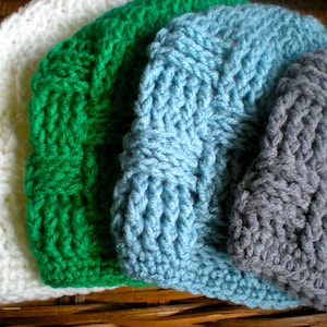 May include: Four knitted hats in different colors: white, green, blue, and gray. The hats are made with a textured stitch and have a simple, classic design.