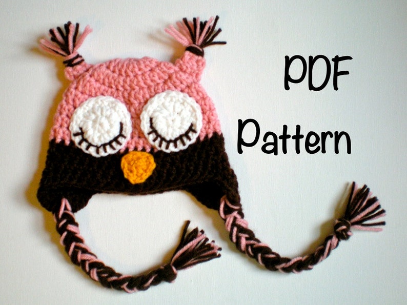 May include: Crochet pattern for an owl hat with pink and brown yarn. The hat has a braided tail and the owl's eyes are closed. The text "PDF Pattern" is visible in the image.