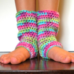 May include: A pair of colorful crocheted leg warmers in shades of pink, green, purple, and blue. The leg warmers are worn on a person's legs.