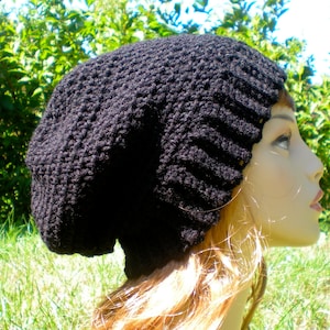 May include: A black slouchy beanie hat with a ribbed texture. The hat is made of a soft, warm material and is perfect for keeping your head warm in the winter.