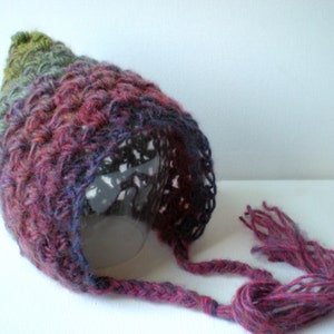 May include: A colorful crocheted hat with a long, dangling tassel. The hat is made with a variety of shades of green, purple, and pink yarn.