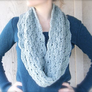 May include: A light blue crocheted infinity scarf with a delicate, lacy pattern.