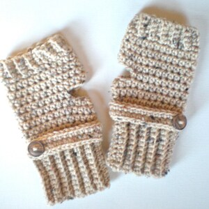 May include: A pair of beige crocheted fingerless gloves with brown buttons. The gloves have a ribbed cuff and a thumb hole.