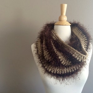 May include: A brown and beige crocheted infinity scarf with a fuzzy texture.