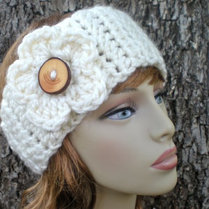 May include: A white crocheted headband with a large white crocheted flower and a wooden button in the center.