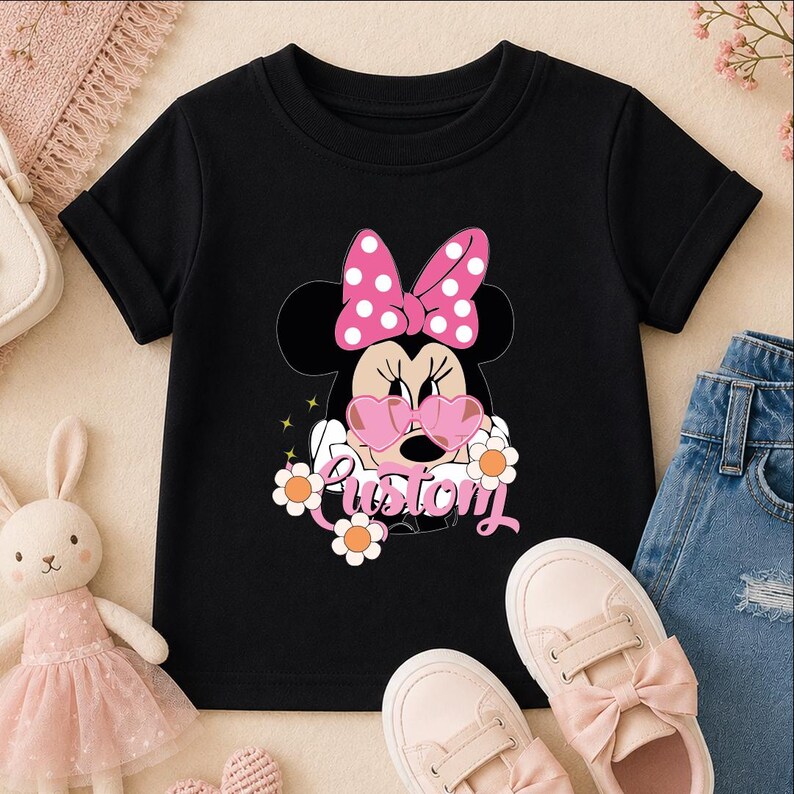 A black t-shirt with a Minnie Mouse design and the word "Pustory" printed on it, along with a pair of pink sneakers and a stuffed bunny rabbit.