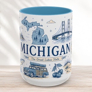May include: A white ceramic mug with a blue interior featuring a Michigan state map, the Mackinac Bridge, a vintage wood-paneled station wagon, and cherries. The text reads MICHIGAN and The Great Lakes State in blue and tan ink on the exterior.