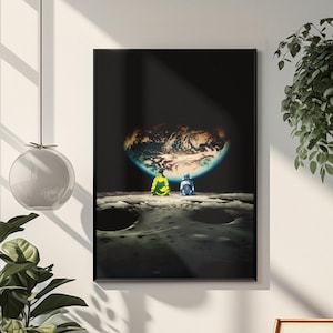 May include: A rectangular wall art print in a black frame featuring a dark space scene. Two figures sit on a cratered lunar surface, looking toward a glowing, illuminated Earth suspended in the black void of space above the horizon line.