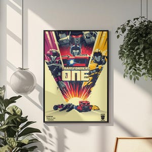 May include: A framed movie poster for Transformers One featuring Optimus Prime, Megatron, and other characters in a vibrant red, yellow, and black color scheme. The text Transformers One is centered with D-Box, RealD 3D, Cinemark, and 2024 printed below.