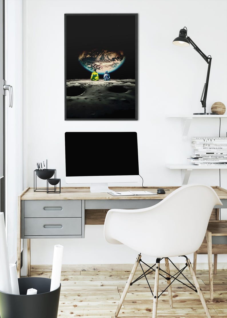 May include: A framed vertical wall art print featuring a dark space scene with two figures sitting on a cratered lunar surface, looking out at a glowing, partially illuminated Earth suspended in the black void of the deep night sky.