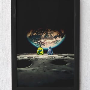 May include: A framed rectangular wall art print featuring an anime-style illustration of two figures sitting on a cratered lunar surface, looking out at a glowing Earth against a deep black space background, enclosed in a simple black frame.
