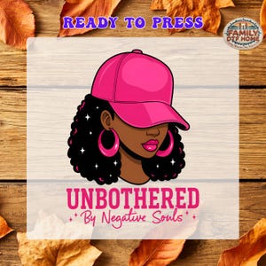 May include: A graphic illustration of a person with dark skin, curly black hair, and large pink hoop earrings, wearing a bright pink baseball cap. The text reads READY TO PRESS, UNBOTHERED By Negative Souls, and FAMILY DTF HOME.