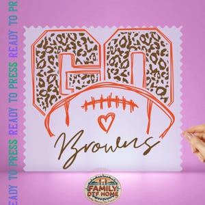 May include: A DTF transfer sheet featuring the text GO in a brown leopard print pattern with orange outlines, a stylized orange football graphic with a heart, and the word Browns in brown script. The text READY TO PRESS is on the left side.