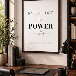 May include: A rectangular wall art print in a dark wood frame featuring the black text KNOWLEDGE IS POWER with a small botanical line drawing underneath and the phrase LEARN DAILY. GROW CONSTANTLY. printed in smaller black font at the bottom.