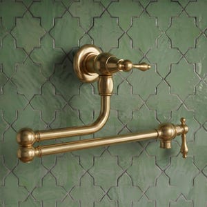 May include: A wall-mounted pot filler faucet with a brushed brass finish, featuring a double-jointed articulating arm and a single lever handle. The fixture has a cylindrical base, two horizontal pipe segments, and a vertical spout end.