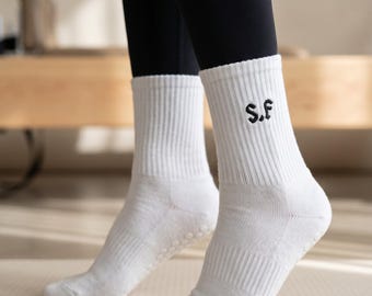 May include: A pair of white ribbed crew socks featuring the black embroidered letters S.F on the outer side of the ankle. The socks have a textured knit construction with small circular grip patterns visible on the soles for added traction.