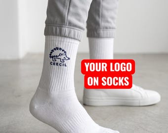May include: White crew socks featuring a dark blue embroidered hedgehog graphic and the text CEECIL on the outer side. The socks are worn with light gray joggers and white sneakers. A red rectangular graphic with white text reads YOUR LOGO ON SOCKS.