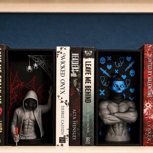 Puede incluir: Una estanter&iacute;a con varios lomos de libros y tres bustos de personajes. Los libros incluyen t&iacute;tulos como Wicked Onyx y Leave Me Behind. Los bustos representan figuras con capucha, una de ellas con una m&aacute;scara de calavera azul e iconos.