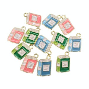 May include: A selection of colourful book charms in pink, green, and blue with gold-tone metal detailing. Each charm features a detailed book design with a white page and a loop for attaching to jewellery or crafts.